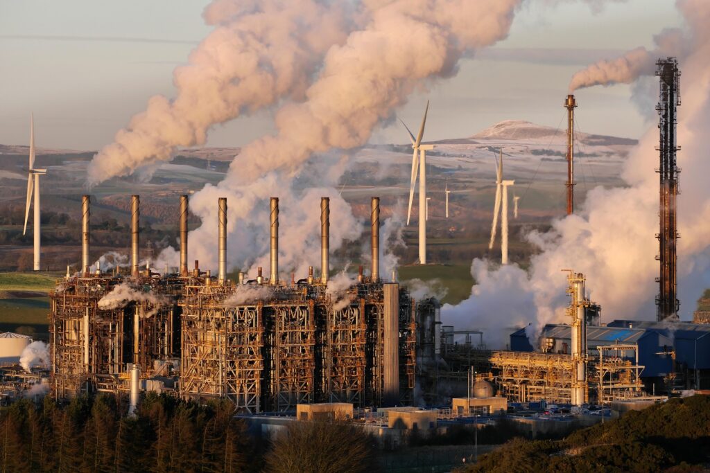 Power plant with smoking chimneys and wind turbines in background