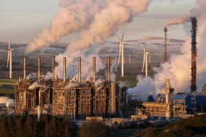 Power plant with smoking chimneys and wind turbines in background